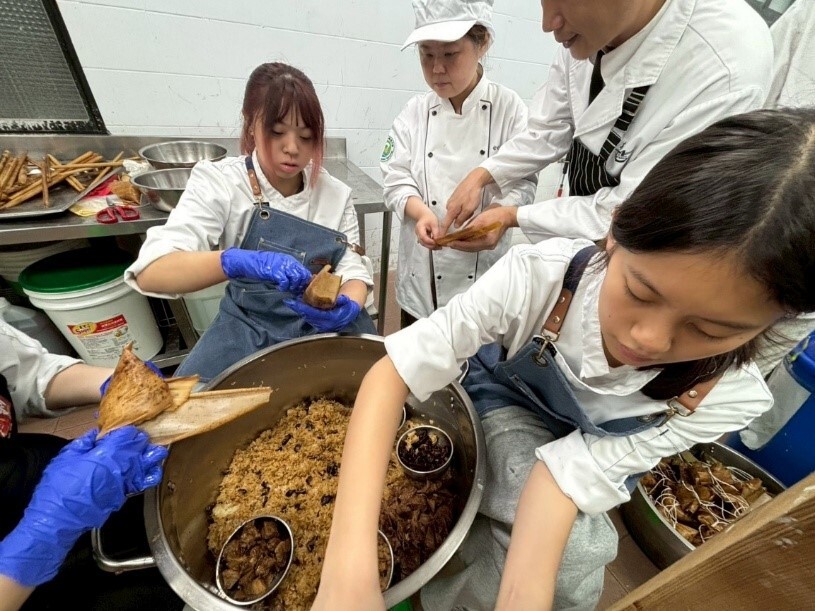 廚房戰場手速全開！同學們一字排開、專注靈活地進行爆量 500 顆香粽的極限製備 。